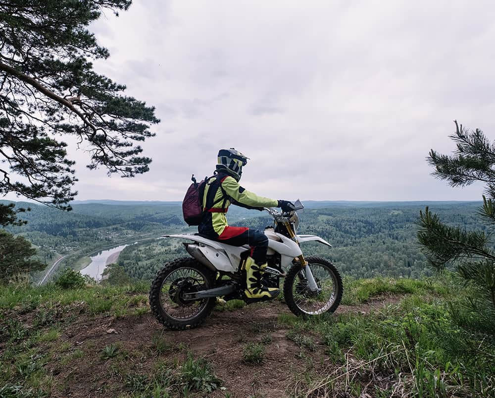 enduro racer on top of a hill overlooking a forest