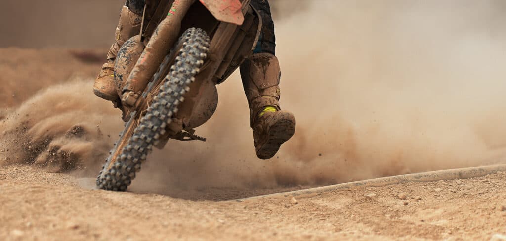 motocross rider going around a corner with dirt and rocks